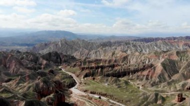 Zhangye, Sunan Bölgesi, Gansu Eyaleti, Çin 'deki Binggou Danxia Kanyonu' nun insansız hava aracı görüntüsü. Geopark 'ta Keskin Sivri Tepeler. Güneşli bir günde Vadideki Yol.