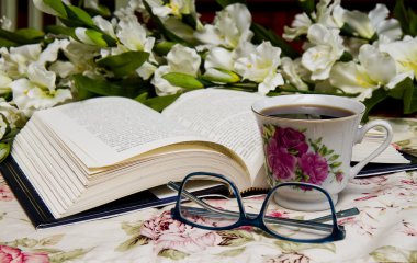 Gözlük, çiçek ve kahve ile açık kitap