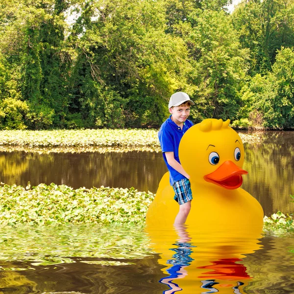 Junge Reitet Auf Einer Riesigen Gummiente Einem Großen Teich Mit — Stockfoto