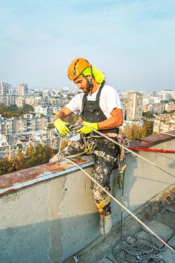 Dış cephe duvarını boyarken binadan sarkan endüstriyel halat işçisi. Endüstriyel dağcılık konsepti. Üst görünüm