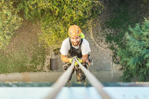 Průmyslový provazový pracovník visící z budovy při natírání vnější fasádní stěny. Koncepce průmyslového alpinismu. Horní pohled — Stock fotografie