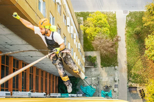 Průmyslový provazový pracovník visící z budovy při natírání vnější fasádní stěny. Koncepce průmyslového alpinismu. Horní pohled — Stock fotografie