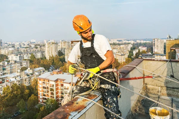 Průmyslový provazový pracovník visící z budovy při natírání vnější fasádní stěny. Koncepce průmyslového alpinismu. Horní pohled — Stock fotografie