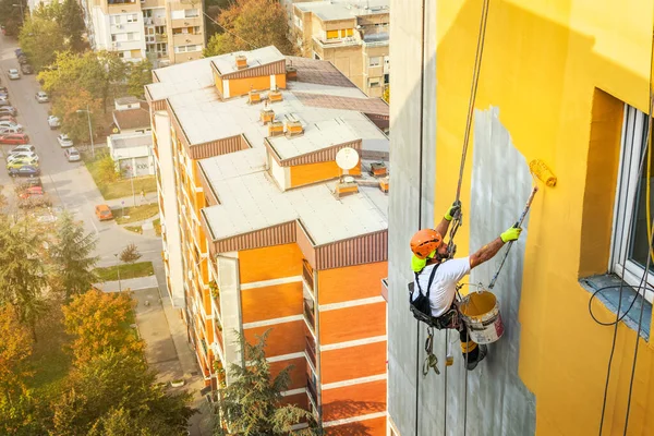 Průmyslový provazový pracovník visící z budovy při natírání vnější fasádní stěny. Koncepce průmyslového alpinismu. Horní pohled — Stock fotografie