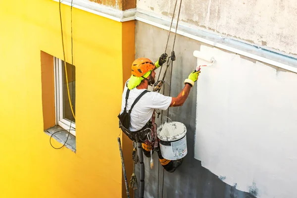 Průmyslový provazový pracovník visící z budovy při natírání vnější fasádní stěny. Koncepce průmyslového alpinismu. Horní pohled — Stock fotografie
