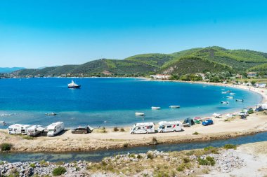 Porto Koufo, Yunanistan, 05 / 07 / 2019: Sahilde park etmiş pek çok eğlence aracı ve turkuaz mavisi suya sahip ünlü Yunan koyuna bakın. Kamp hayatı için mükemmel bir tatil yeri..