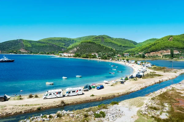 Porto Koufo, Yunanistan, 05 / 07 / 2019: Sahilde park etmiş pek çok eğlence aracı ve turkuaz mavisi suya sahip ünlü Yunan koyuna bakın. Kamp hayatı için mükemmel bir tatil yeri..