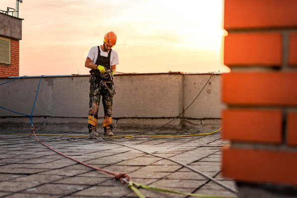 Industrial climber hanging on the rope while painting the exterior facade wall of the tall apartment building. Industrial alpinism and high risk work scene concept image