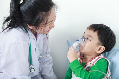 Asyalı çocuk solunum yolu hastalığı sağlık profesyonel tarafından inhaler ile yardımcı olan.