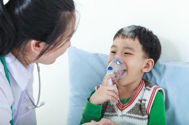 Asyalı çocuk solunum yolu hastalığı sağlık profesyonel tarafından inhaler ile yardımcı olan.