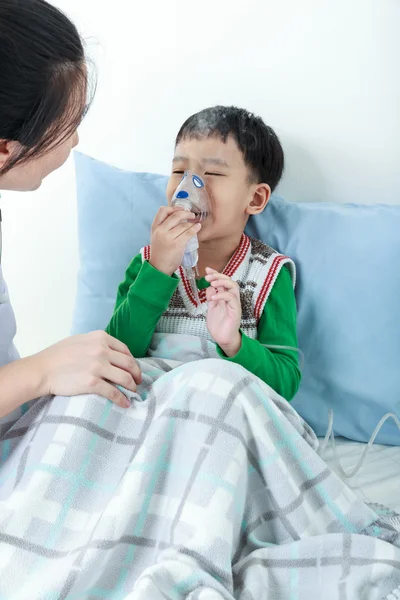 Asiático chico teniendo enfermedad respiratoria ayudado por el profesional de la salud con inhalador . — Foto de Stock