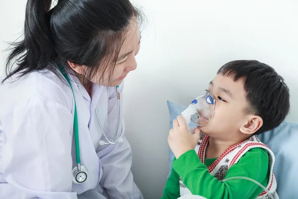 Asiático chico teniendo enfermedad respiratoria ayudado por el profesional de la salud con inhalador . — Foto de Stock