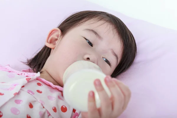 クローズ アップかわいいアジアの女の子は、牛乳瓶を吸います。健康のために牛乳を飲む. — ストック写真