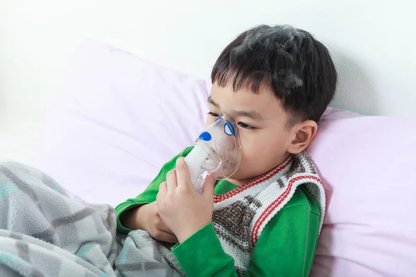 Niño asiático sostiene un inhalador de vapor máscara para el tratamiento del asma . — Foto de Stock