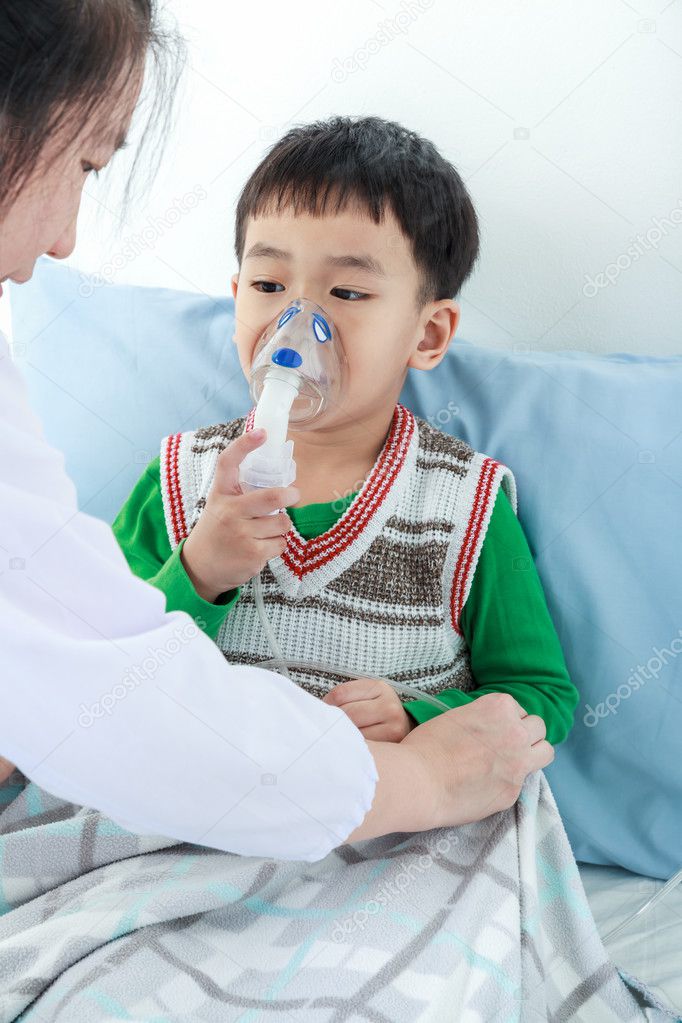 Asian boy having respiratory illness helped by health professional with inhaler. 