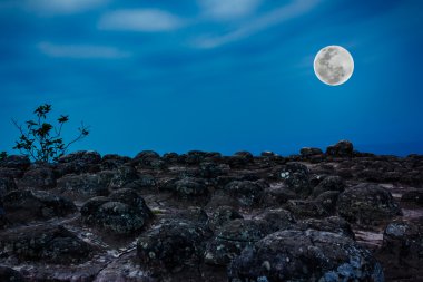 Rocky against blue sky and beautiful full moon at night. Outdoor clipart
