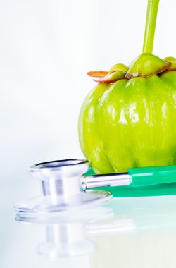 Closeup garcinia cambogia and stethoscope on white background.  clipart