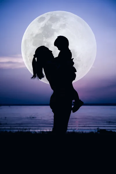 Вид сбоку силуэта матери и ребенка, наслаждающихся большой луной — стоковое фото