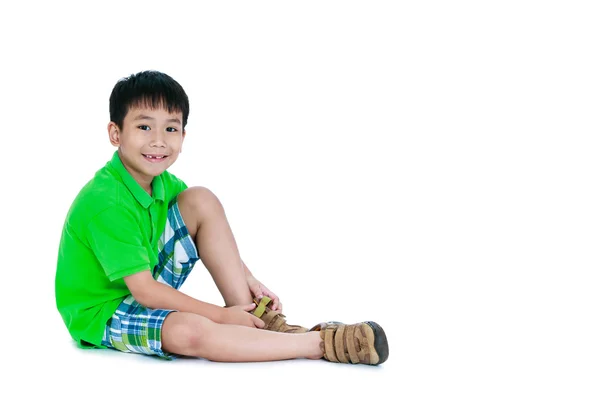 Widok z boku z Azji dziecko umieścić skórzane buty na. Na białym tle. — Zdjęcie stockowe