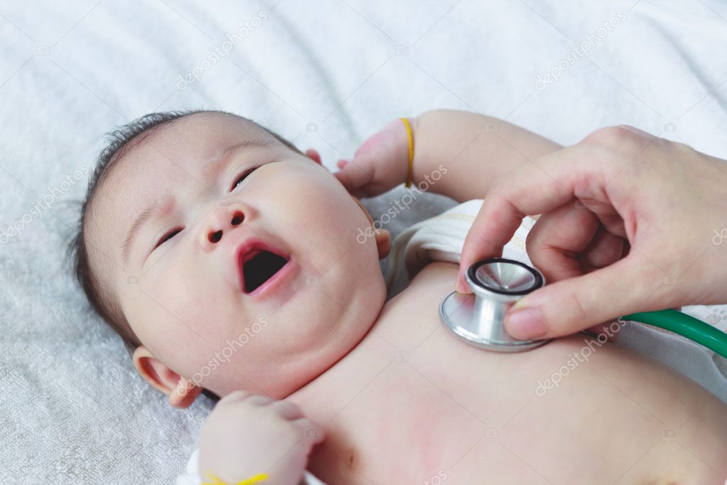 Pediatrician examining infant. Two months baby asian girl lying 