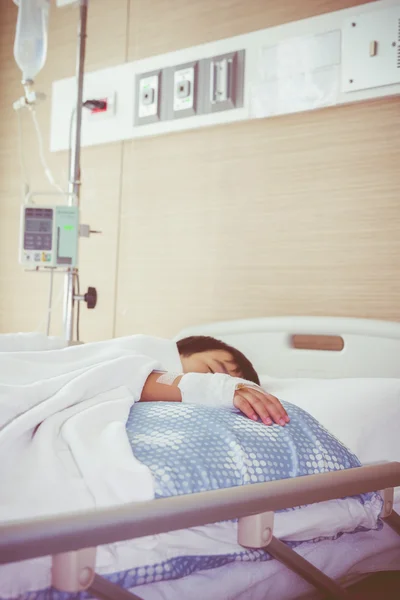 Niño asiático acostado en cama enferma con solución salina intravenosa (IV). Concepto de salud y personas . — Foto de Stock