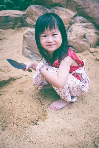 Urocza dziewczyna azjatyckich ma zabawy, kopać w piasku w letni dzień — Zdjęcie stockowe
