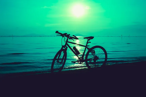 Sylwetka roweru na plaży przed kolorowy zachód słońca na morzu — Zdjęcie stockowe