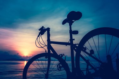 Denizin içinde renkli günbatımı karşı sahilde Bisiklet silüeti.