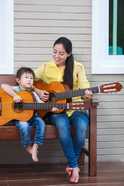 Matka z córka grać na gitarze. Rodzinie spędzać czas razem w domu. — Zdjęcie stockowe
