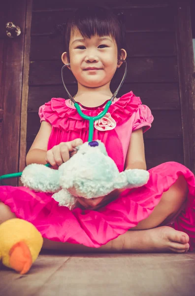 Primer plano adorable asiático chica jugando doctor o enfermera con peluche juguete oso en casa . —  Fotos de Stock