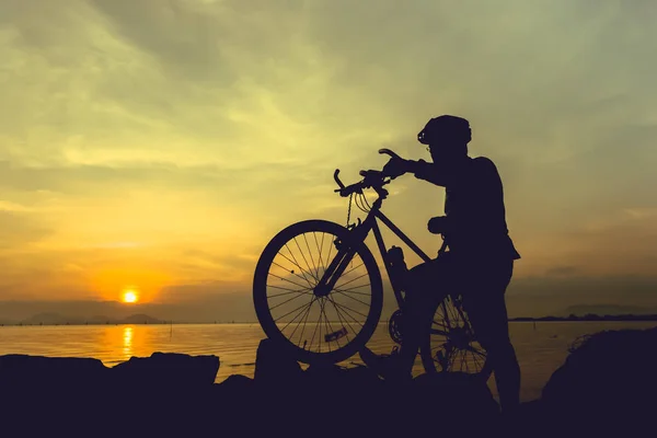 健康的生活方式。骑自行车的人站在海边的自行车的剪影 — 图库照片