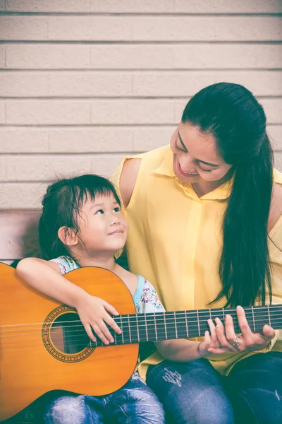 母亲与女儿弹吉他。花时间在一起的家庭。小插图和复古风格. — 图库照片