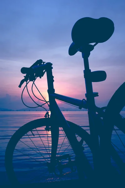 Fahrradsilhouette am Strand gegen bunten Sonnenuntergang im Meer. — Stockfoto