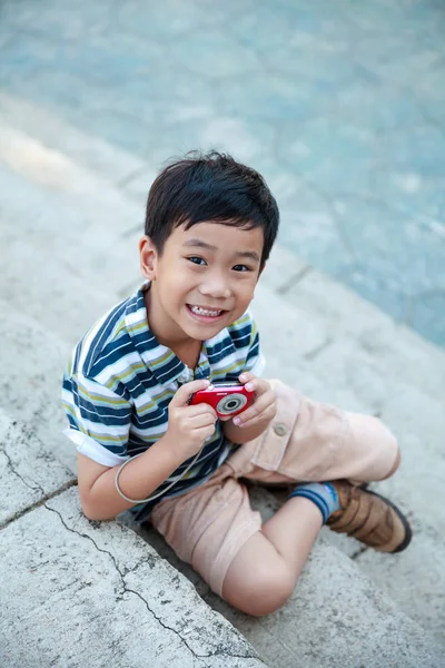 Happy asian boy with camera relaxing outdoors in the day time — Stock Photo, Image
