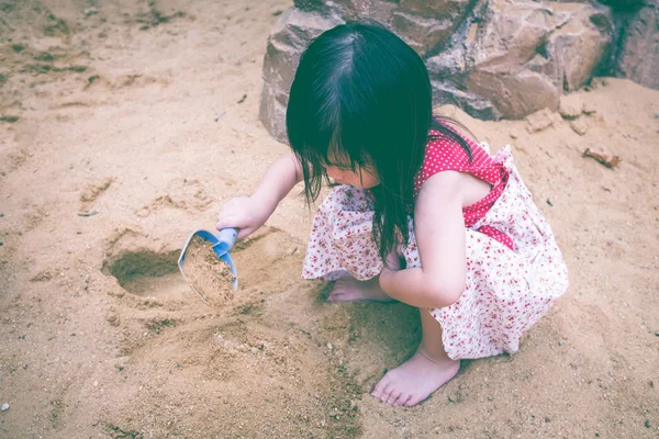 Güzel Asyalı kız eğlenceli bir yaz günü kum kazma. — Stok fotoğraf