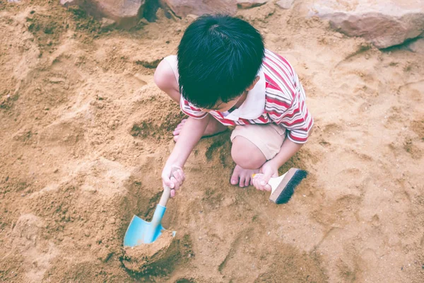 Vista dall'alto. Adorabile asiatico ragazzo ha divertimento scavare nella sabbia su un su — Foto Stock