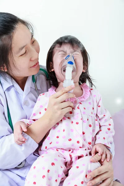 Bambino asiatico con malattia respiratoria aiutato da professionisti della salute con inalatore . — Foto Stock