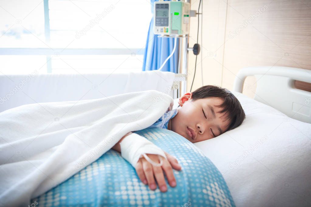 Asian boy lying on sickbed with saline intravenous (IV).