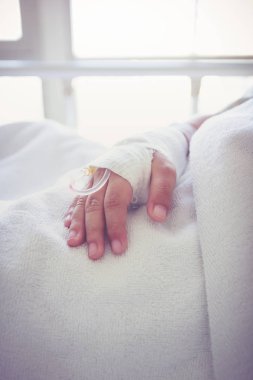 Bir çocuğun hasta el içinde serum fizyolojik Intravenous (IV) damla. Vintage sesi.