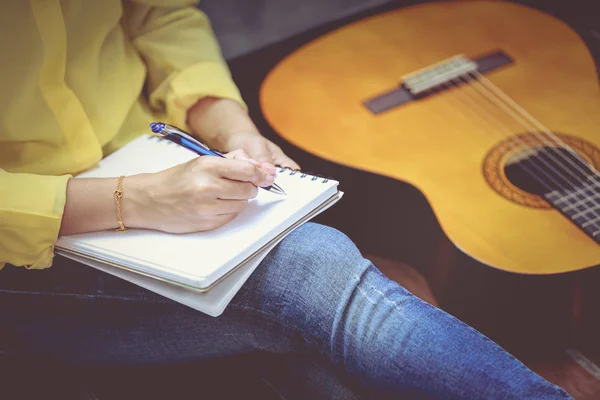Escritura de primer plano de compositor en papel de nota con guitarra acústica cerca . —  Fotos de Stock