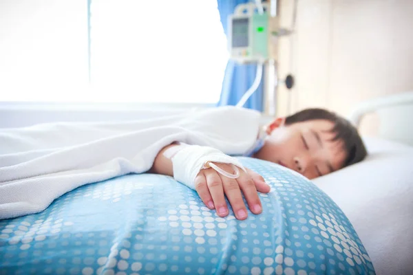 Niño asiático acostado en cama enferma con solución salina intravenosa (IV). Atención de la salud y concepto de personas . —  Fotos de Stock