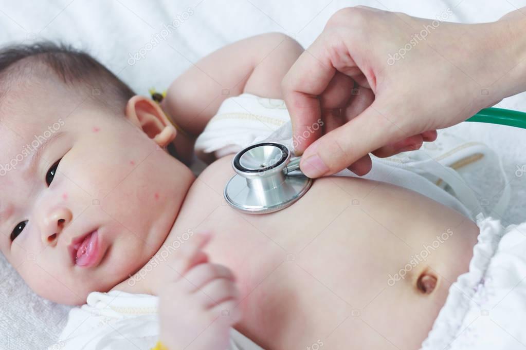 Pediatrician examining infant. Two months baby asian girl lying 