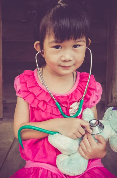 Detailní záběr roztomilé asijské dívky hrací lékař nebo sestra s plyšovou hračkou — Stock fotografie