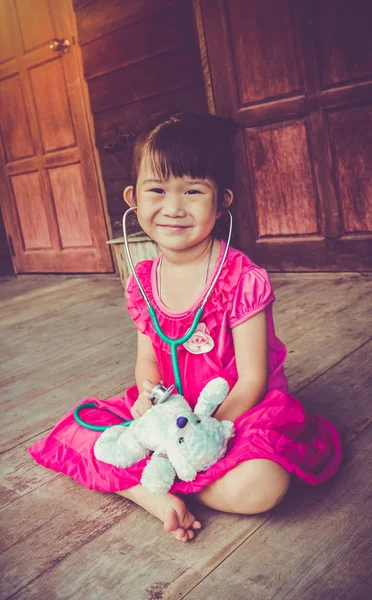 Urocza dziewczyna azjatyckich zbliżenie gra lekarz lub pielęgniarka z pluszową zabawką niedźwiedź w domu. — Zdjęcie stockowe