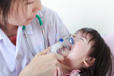 Asyalı kız doktor tarafından inhaler ile yardımcı solunum yolu hastalığı olan.