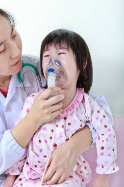 Asyalı kız doktor tarafından inhaler ile yardımcı solunum yolu hastalığı olan.