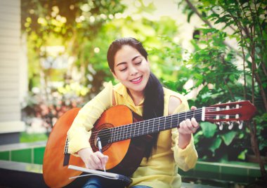 Akustik gitar ile bir not kağıdına yazmak güzel söz yazarı 