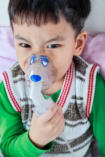 Primer plano de niño asiático enojado sostiene un inhalador de vapor máscara para el tratamiento del asma —  Fotos de Stock