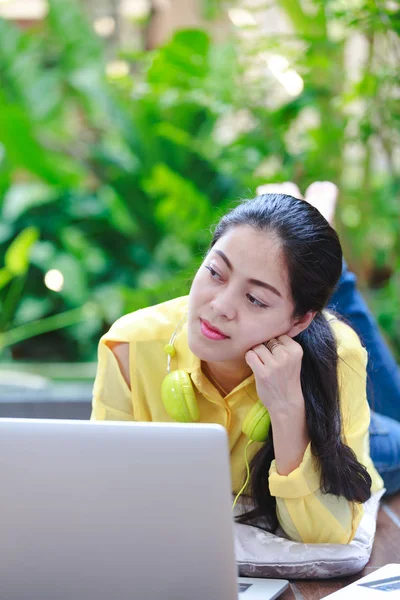 Leende asiatisk kvinna använder bärbar dator med hörlurar. — Stockfoto