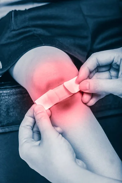 Mother provides first-aid at wound on son leg with red spot sore area. — Stock Photo, Image